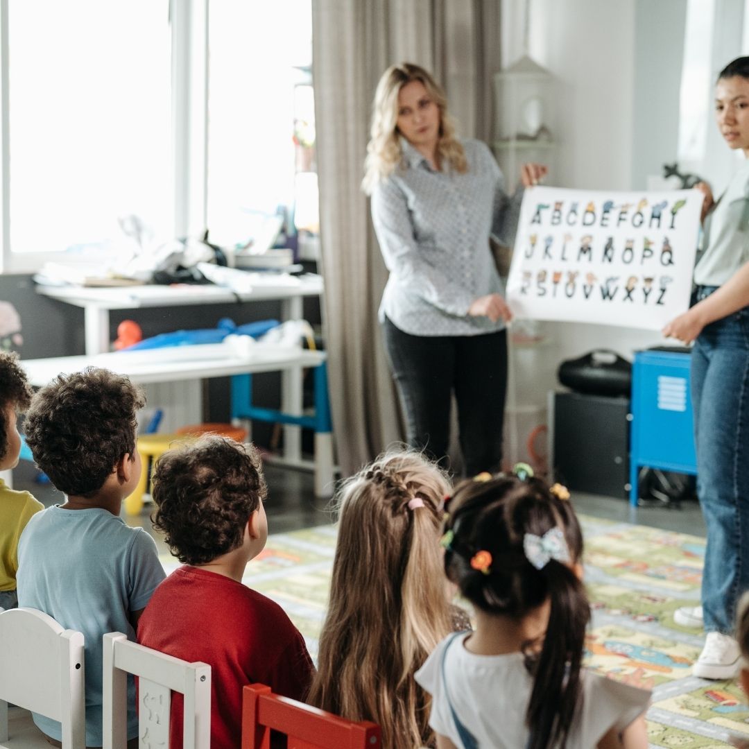 teachers holding an alphabet poster