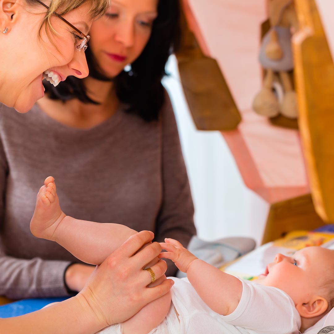 Smiling woman playing with happy baby