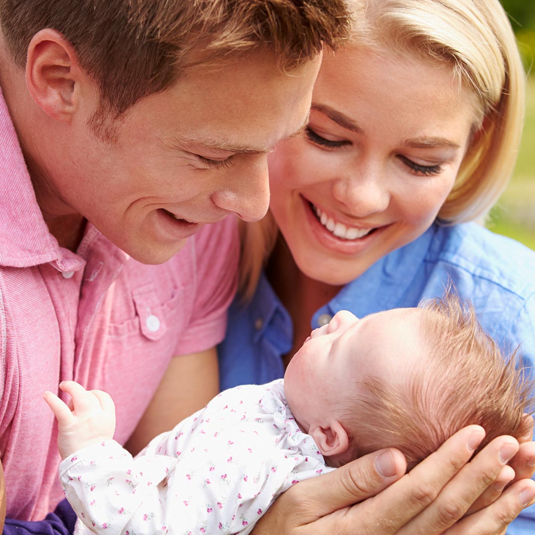 Mother and father holding and smiling at their infant child
