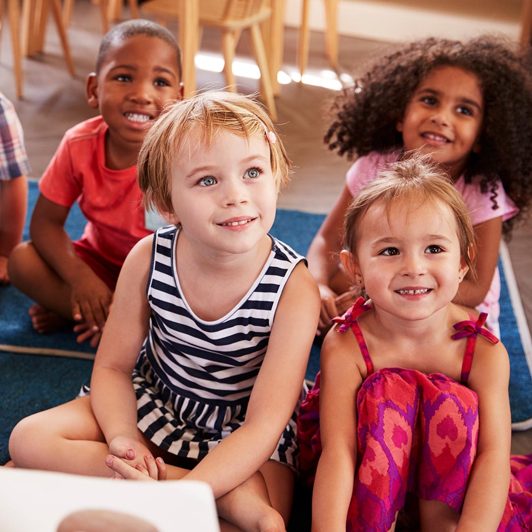 group of kids sitting on a mat at preschool