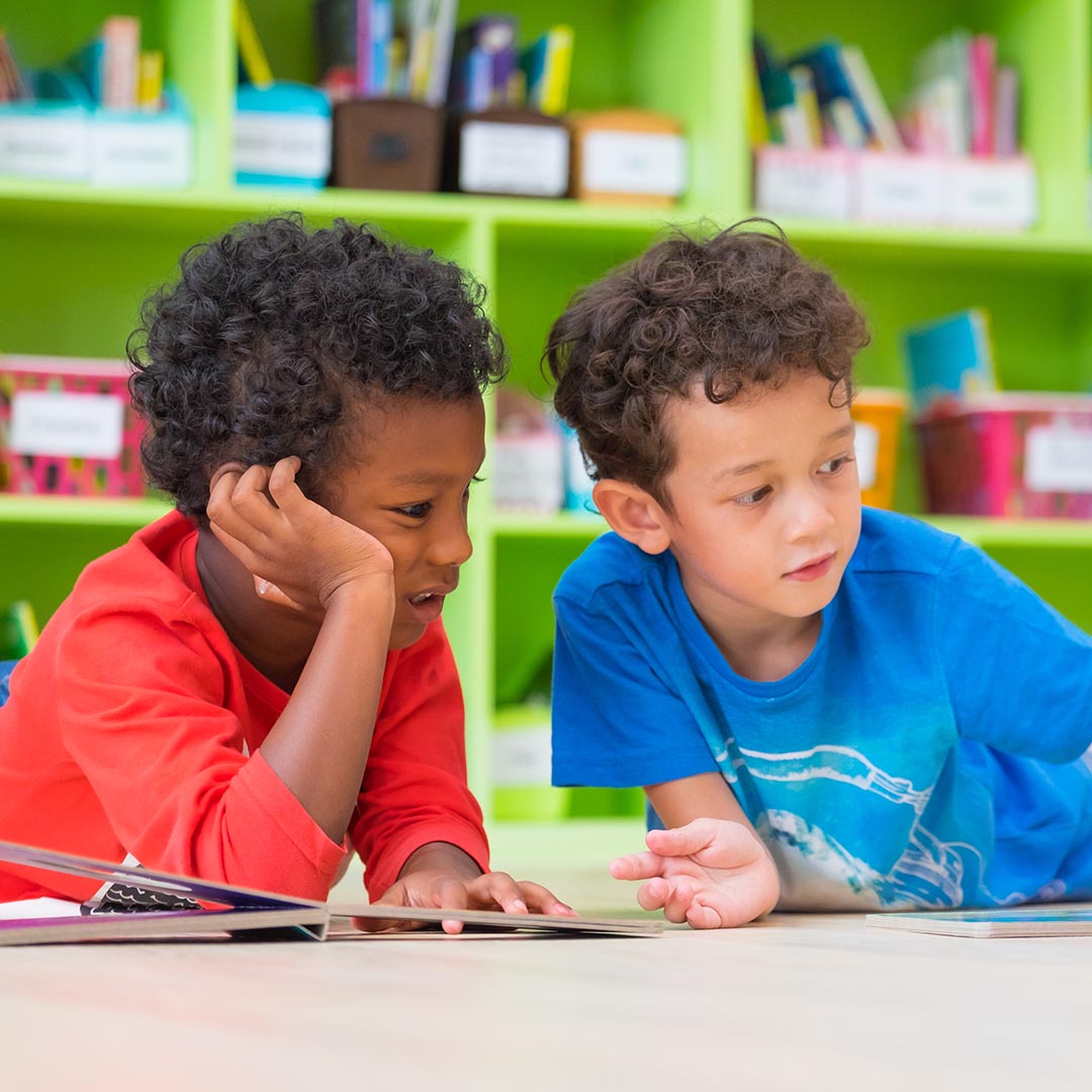 two boys in preschool looking at books