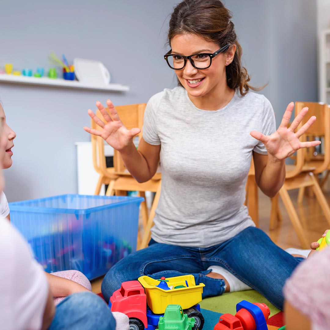 smiling preschool teacher holding up all her fingers as counting to 10