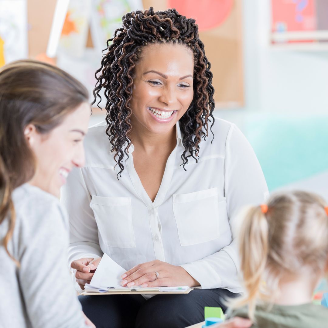 a teacher smiling at a mom and daughter