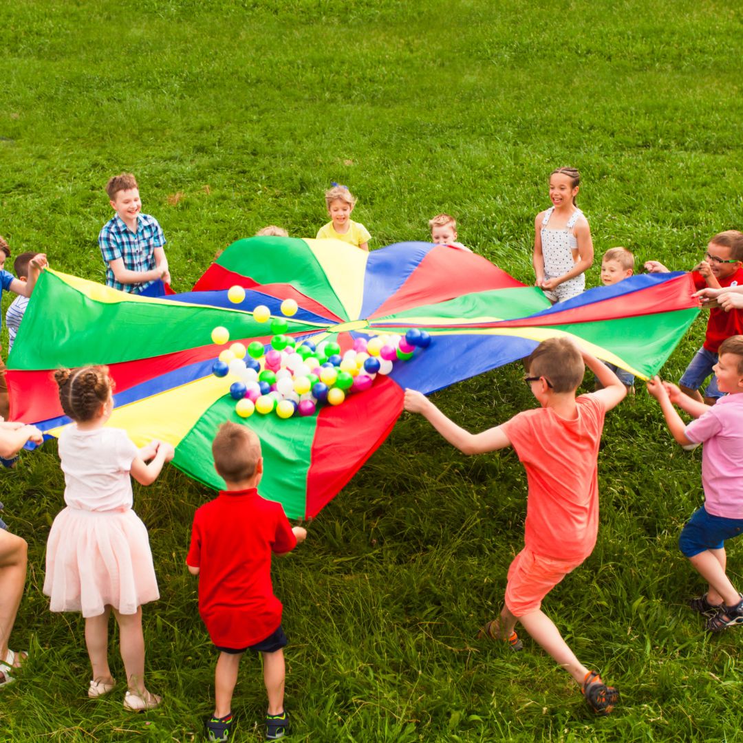 Kids playing with a parachute outside.