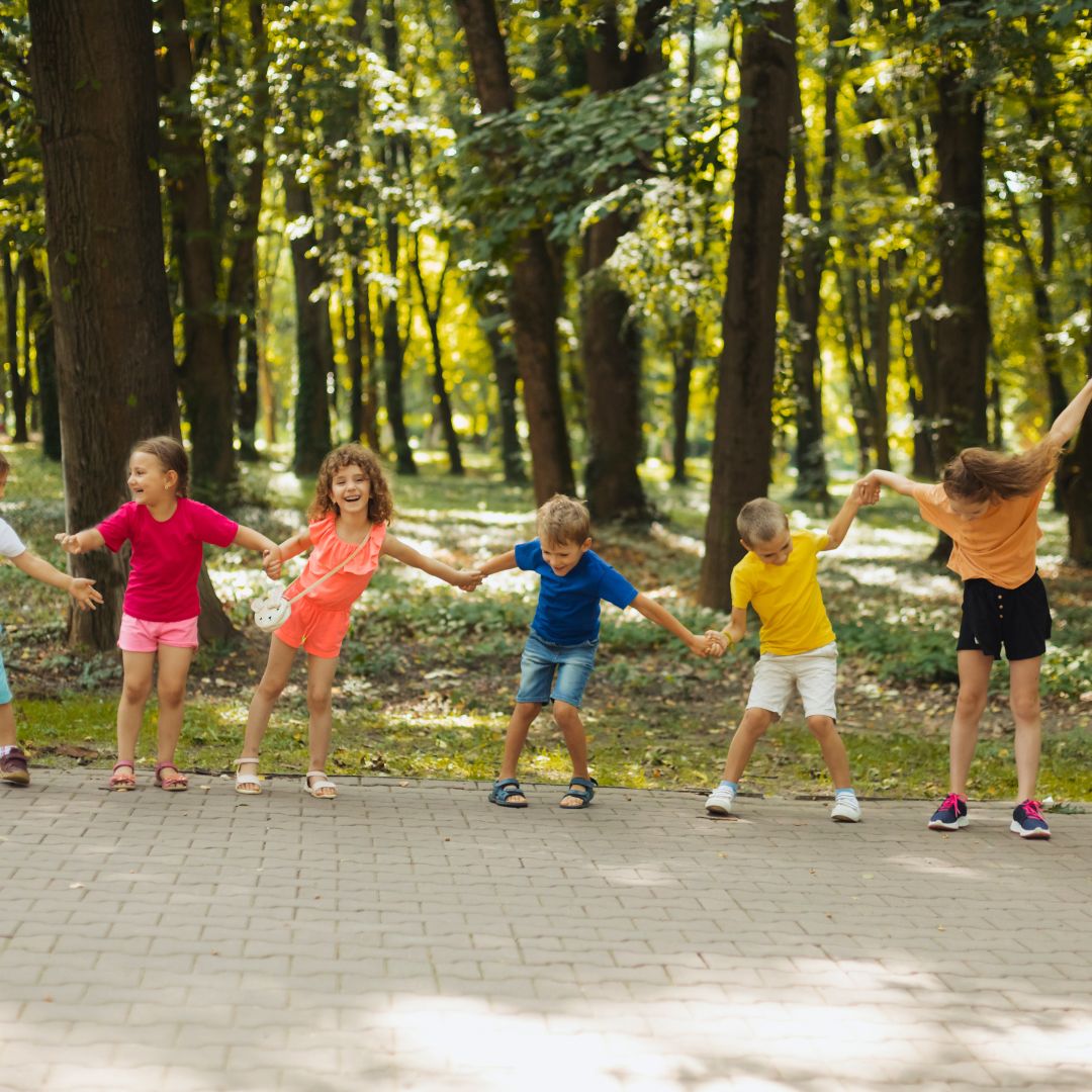 Kids holding hands and dancing outside.