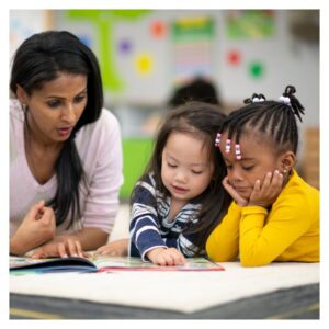 woman sits with 2 young kids looking at book 