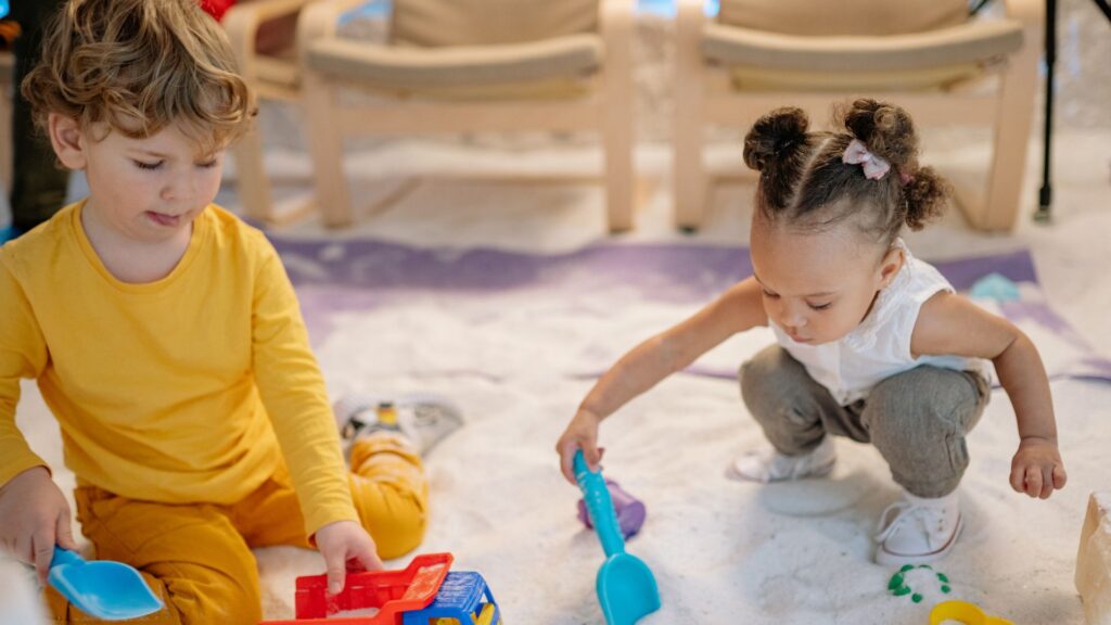 boy and girl play with shovels in sandbox