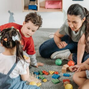 group of kids play on floor with teacher