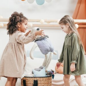 girls play together taking stuffed animals out of bin
