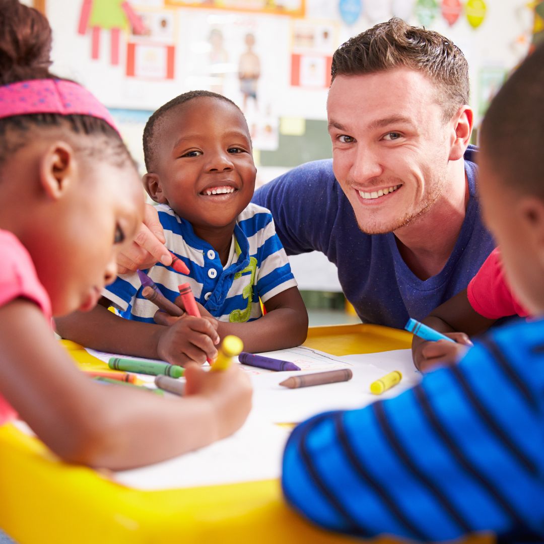 smiling preschoolers and teacher at table