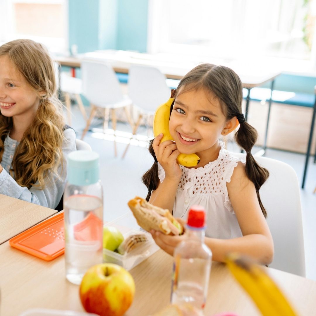 young child eating and pretending banana is a phone