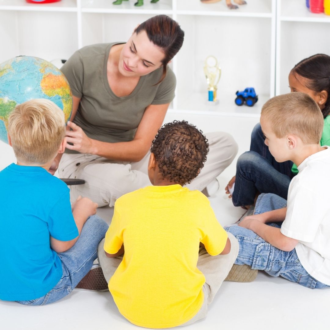 A teacher showing a globe to young children.